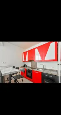 a kitchen with red cabinets and a table and chairs at Appartement 3 pièces in Nice