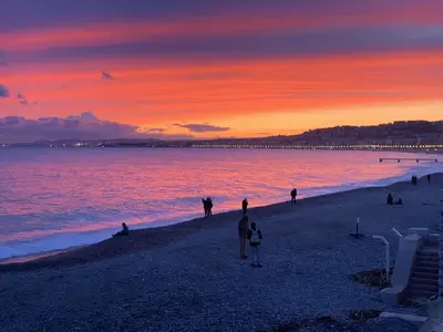 a group of people standing on a beach at sunset at Nid perché avec aperçu mer Tout à pied ! in Nice