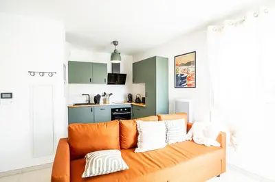 an orange couch in a living room with a kitchen at Le Neoroch in Nice
