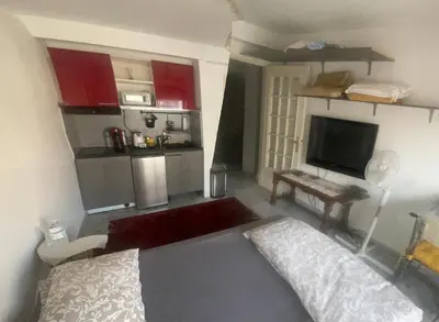 a bedroom with a bed and a kitchen with red cabinets at Studio 112 in Nice