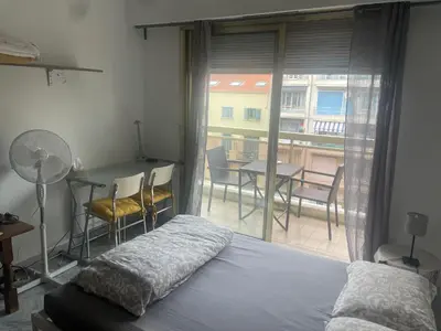 a bedroom with a bed and a balcony with a table and chairs at Studio 112 in Nice