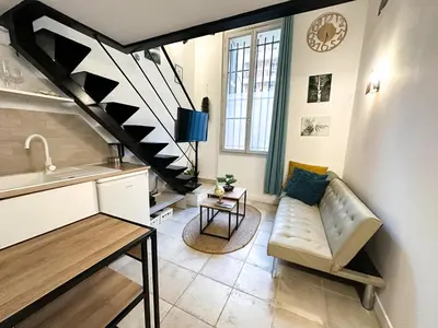 a living room with a couch and a spiral staircase at AngeVert HolidayHouse in Nice
