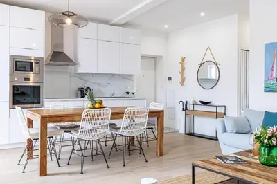 a kitchen and living room with a wooden table and chairs at Sunlight Properties - Archibald - Nice Port area, 2 Bedrooms, stunning holiday rental apartment with balcony & parking in Nice
