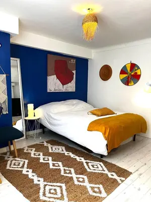 a bedroom with a bed with a blue wall at Le Bohème 3 pièces jardin in Saint-Laurent-du-Var