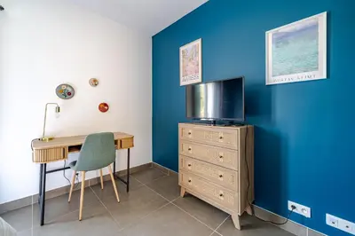 a room with a desk and a tv on a blue wall at Maison niçoise vue dégagée avec jacuzzi privatif in Nice