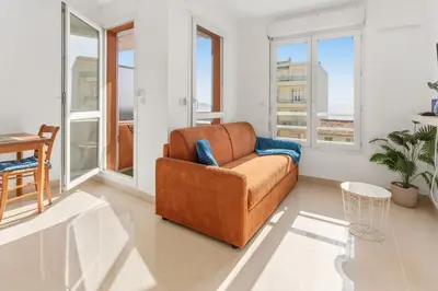 a living room with a couch and a clock on the wall at L'Azur - Seaview - AC - Tram - WIFI - Airport in Nice