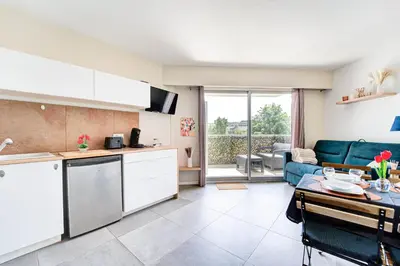 a kitchen and living room with a couch and a table at Sandaya - 10min à pied de la Plage in Cagnes-sur-Mer