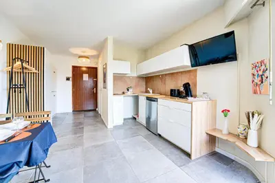 a kitchen with white cabinets and a table in a room at Sandaya - 10min à pied de la Plage in Cagnes-sur-Mer