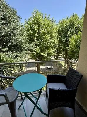 a blue table and chairs on a balcony with trees at Big Apartement 20 min from beach in Nice