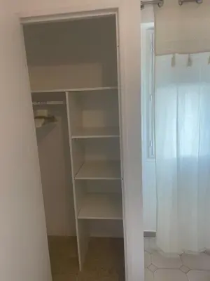 a walk in closet with shelves and a shower at Sun appart in Nice
