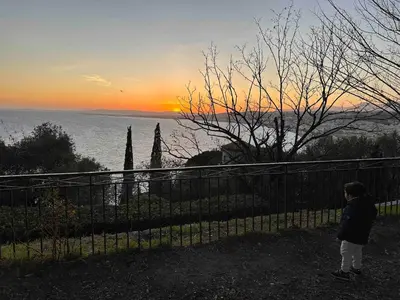 a person standing next to a fence at sunset at Bella Nissa Bnb - AC wifi - cosy - 2 bedrooms in Nice