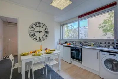 a kitchen with a table and a clock on the wall at Castel du Port - Happy Rentals in Saint-Laurent-du-Var