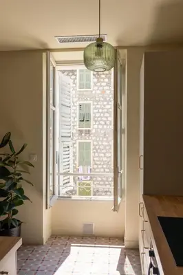 a kitchen with a large window and a pendant light at Le charme de l'ancien, rénové - Nice - 4 personnes in Nice