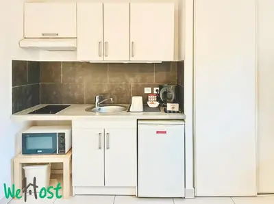 a kitchen with white cabinets and a sink and a microwave at WeHost Carnot - Bail Mobilité ONLY - Escapade côté Port pour 2 in Nice