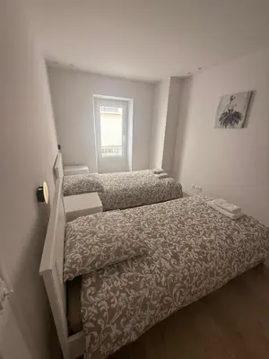 a small bedroom with two beds and a window at Appartement Duplex Bord de Mer in Cagnes-sur-Mer