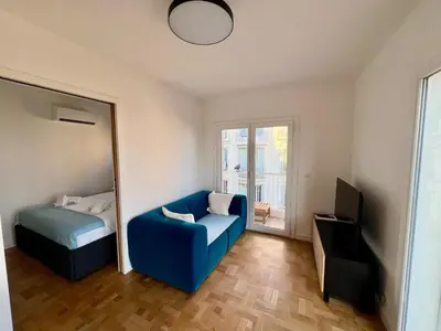 a bedroom with a blue couch and a bed and a mirror at Appartement Vue Mer T2 Cosy, Plage à pied 3 mins, Coucher de Soleil, Parc privé in Nice
