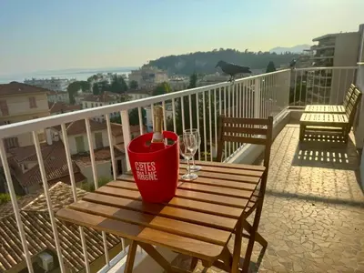 a red drink container sitting on a wooden bench on a balcony at Appartement Vue Mer T2 Cosy, Plage à pied 3 mins, Coucher de Soleil, Parc privé in Nice