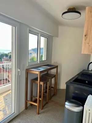 a kitchen with a table with two chairs and a window at Appartement Vue Mer T2 Cosy, Plage à pied 3 mins, Coucher de Soleil, Parc privé in Nice
