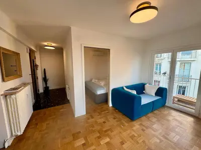 a living room with a blue couch and a window at Appartement Vue Mer T2 Cosy, Plage à pied 3 mins, Coucher de Soleil, Parc privé in Nice