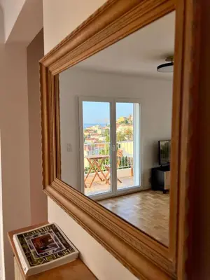 a mirror with a reflection of a room with a window at Appartement Vue Mer T2 Cosy, Plage à pied 3 mins, Coucher de Soleil, Parc privé in Nice
