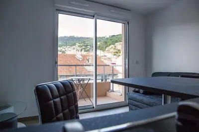 a room with a table and chairs and a large window at Studio climatisé au calme, mezzanine et balcon in Nice