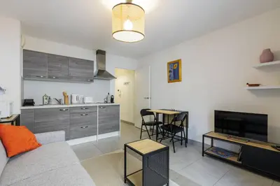 a living room with a couch and a table and a kitchen at Studio au port de nice in Nice