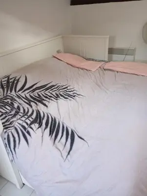 a bed with a black and white comforter on it at Appartement meublé 265 in Nice