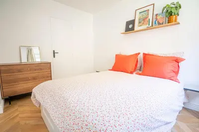 a bedroom with a bed with orange pillows and a dresser at Superbe 2 pièces contemporain au cœur de Nice in Nice