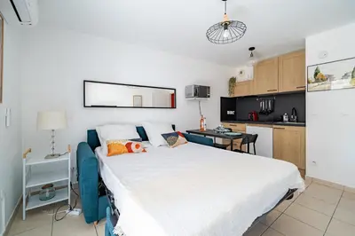a bedroom with a large bed and a kitchen at Studio port de Nice Clim Balcon in Nice