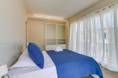 a bedroom with a blue bed with a large window at Dina palace AP4462 By Riviera Holiday Homes in Villefranche-sur-Mer