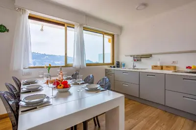 a kitchen with a table with chairs and a large window at Dina palace AP4462 By Riviera Holiday Homes in Villefranche-sur-Mer