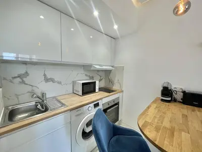 a kitchen with a sink and a table with a blue chair at Nice Signature Andrioli in Nice