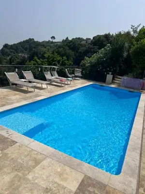 a blue swimming pool with lounge chairs and trees at Amoremio studio Saint Laurent du Var in Saint-Laurent-du-Var