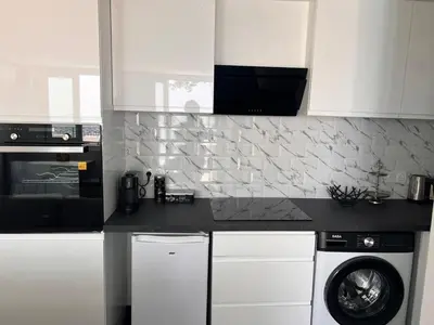 a kitchen with white cabinets and a washing machine at Amoremio studio Saint Laurent du Var in Saint-Laurent-du-Var