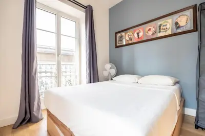 a bedroom with a large white bed and a window at Guest House La Niçoise in Nice