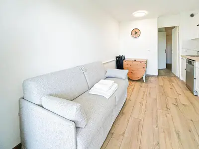 a living room with a gray couch and wooden floors at Élégance Azuréenne - piscine et parking in Villefranche-sur-Mer