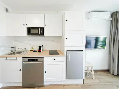 a kitchen with white cabinets and a stainless steel dishwasher at Élégance Azuréenne - piscine et parking in Villefranche-sur-Mer