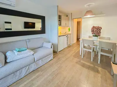 a living room with a couch and a table and a kitchen at Ange Gardien - AC, Parking, Piscine in Villefranche-sur-Mer