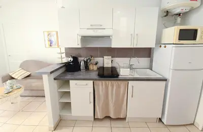 a kitchen with white cabinets and a white refrigerator at L'Appart by la Maïoun Guesthouse in Nice