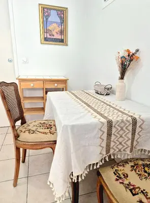 a dining room with a table and chairs and a vase of flowers at L'Appart by la Maïoun Guesthouse in Nice
