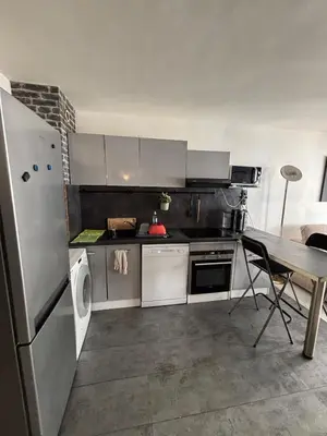 a kitchen with a stainless steel refrigerator and a table at Charmant 2 pièce à 2min de la mer in Nice