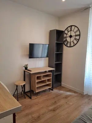 a room with a desk with a tv and a clock at Studio 1 pièce in Nice