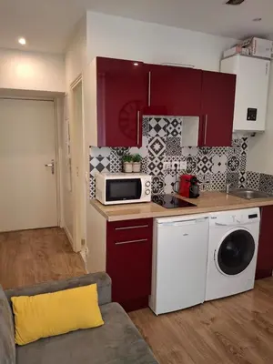 a small kitchen with red cabinets and a microwave at Studio 1 pièce in Nice