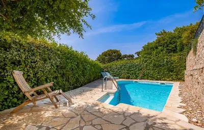 a swimming pool with a bench and a chair next to a hedge at Beautiful Home In Eze in Èze