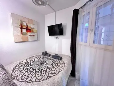 a bedroom with a bed and a flat screen tv at Rez de jardin privatif à 150m de la mer in Villefranche-sur-Mer