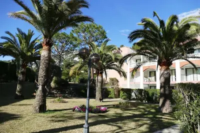 a street light in front of a building with palm trees at Rez de jardin privatif à 150m de la mer in Villefranche-sur-Mer