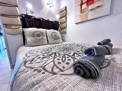 a bedroom with a bed with a blanket and pillows at Rez de jardin privatif à 150m de la mer in Villefranche-sur-Mer