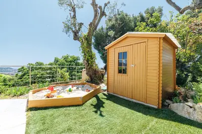 a wooden play house with a sandbox in the grass at VILLA MONTE CRISTO - Villa conviviale a Nice - Superbe vue, piscine et jeux en plein air in Nice