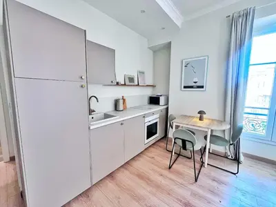 a kitchen with white cabinets and a table and a sink at Ref 119 - Slow Riviera T2 - Rue de France in Nice