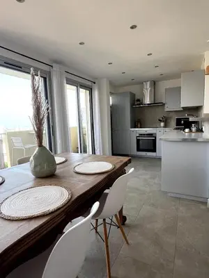 a kitchen and dining room with a wooden table and chairs at Lea's cozy nest with a sea-mountain view in Saint-Laurent-du-Var
